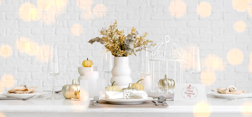 Elegant table serving with pumpkins and burning candles for Thanksgiving dinner in light room