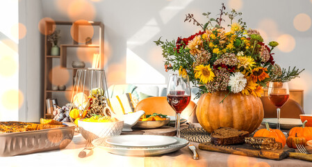 Pumpkin with autumn bouquet on festive dining table in room, closeup