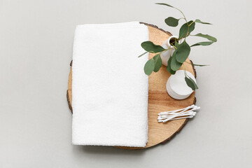 Composition with clean soft towel, wooden tray, cotton pads and buds on grey background