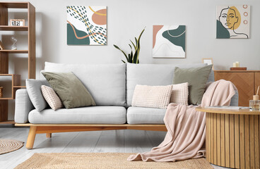 Stylish interior of living room with sofa, coffee table and pictures on wall