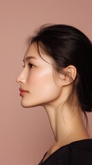 Fototapeta premium Elegance captured in profile with serene expression against soft pink backdrop during a studio photoshoot.