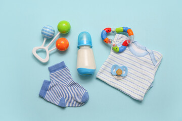 Bottle with milk for baby, clothes and toys on color background