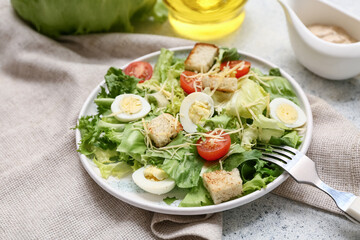 Plate with tasty Caesar salad and gravy boat of sauce on white background