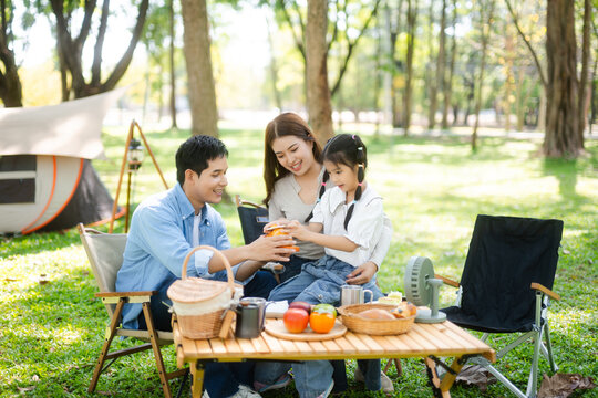 Family enjoys summer camping with coffee, breakfast, and music in nature. Parents and kids bond outdoors