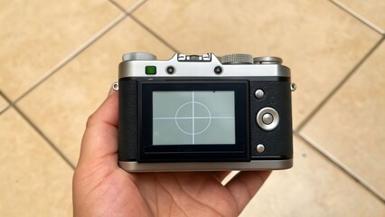 Hand holding digital photo camera with screen and lens closeup