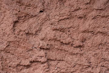 Detailed macro photo of rustic brown clay wall with rough structure, cracks, and natural earthy surface. Ideal for texture backgrounds and design use.