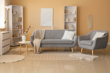 Interior of living room with sofa, armchair and cotton flowers in vase