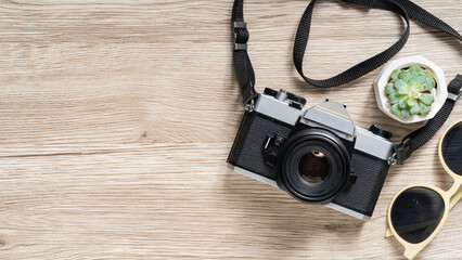 Stylish vintage camera and trendy sunglasses on a wooden surface create a cool travel vibe