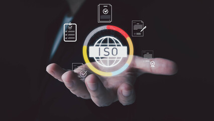 A business person's hand presents a glowing digital icon for international standards certification, surrounded by document and quality check symbols on a dark background.