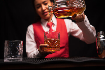 Bartender woman pours whiskey into a glass in a restaurant.	
