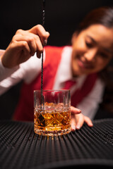 Bartender woman pours whiskey into a glass in a restaurant.	
