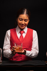 Bartender woman pours whiskey into a glass in a restaurant.	