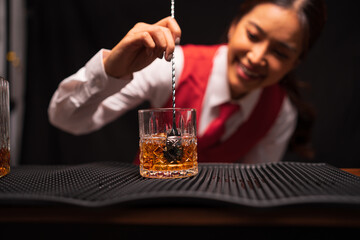 Bartender woman pours whiskey into a glass in a restaurant.	
