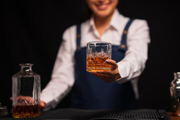 Bartender woman pours whiskey into a glass in a restaurant.	
