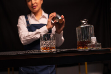 Bartender woman pours whiskey into a glass in a restaurant.	
