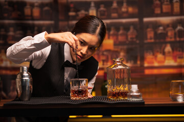  Bartender woman pours whiskey into a glass in a restaurant.