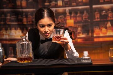  Bartender woman pours whiskey into a glass in a restaurant.