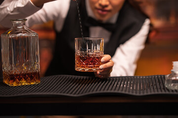Bartender woman pours whiskey into a glass in a restaurant.	
