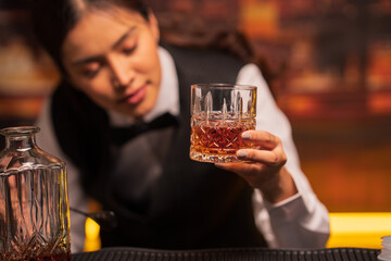 Bartender woman pours whiskey into a glass in a restaurant.	
