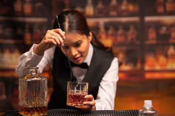 Bartender woman pours whiskey into a glass in a restaurant.