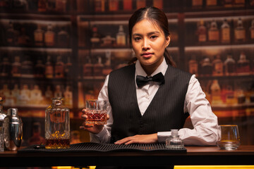 Bartender woman pours whiskey into a glass in a restaurant.	
