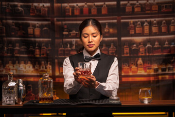  Bartender woman pours whiskey into a glass in a restaurant.