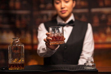  Bartender woman pours whiskey into a glass in a restaurant.
