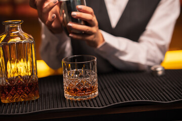 Bartender woman pours whiskey into a glass in a restaurant.	

