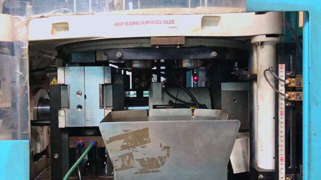 Blow molding machine producing clear plastic bottles on factory production line.