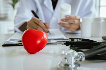A red heart and a stethoscope are placed on a table in a hospital, symbolizing healthcare, diagnosis, heart disease, treatment and care.