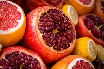 A pile of fresh fruit. In the center of the composition is a pomegranate cut in half, with bright...