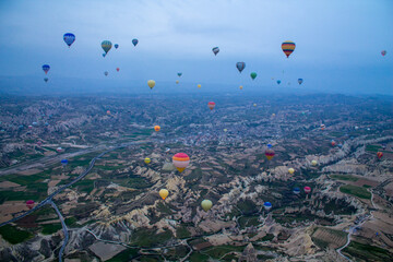 Numerous hot air balloons soar in the sky above a picturesque valley. The image is suitable for themes related to travel, adventure, tourism, and nature. © Юлия Кузьмина