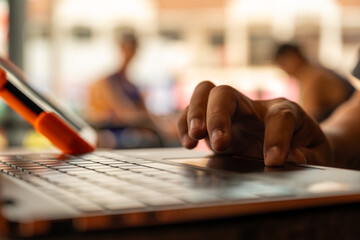 Hand holding stylus writing on tablet in a cozy cafe environment, symbolizing digital creativity, remote working, coffee shop lifestyle, and modern technology-driven workspace.