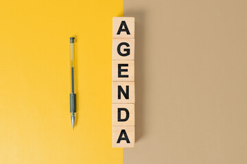 Agenda word on wooden cubes on yellow and cream background