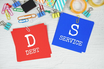 DS - Debt Service text on stick note with stationery on concrete background