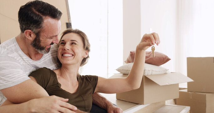 New house, moving and couple with keys, hug or happiness for mortgage approval, love and investment. Man, affection and bonding with woman in lounge, excited and purchase of home with loan or bond - Powered by Adobe