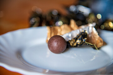 Round chocolate candy served on a white plate, with elegant presentation and rich dark texture. 