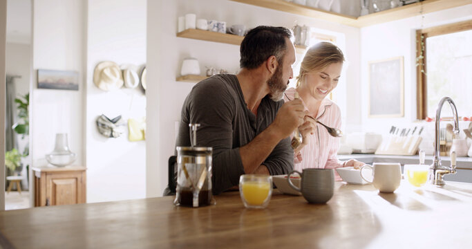 Happy, couple and eating breakfast in kitchen for health, nutrition and diet with partner. Hungry, man and woman with morning meal, cereal and enjoy food together with conversation for love in home