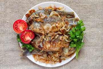 Fried fish on a plate with vegetables. Fresh fried carp