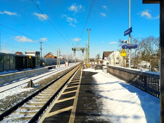 Fototapeta premium havas vasútállomás a sínekkel, házakkal és kék égbolttal.