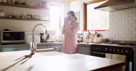 Home, drinking coffee and woman in kitchen, morning and start day with lens flare. Apartment, mug and person with hot beverage, caffeine and peace with espresso, cappuccino and me time with break