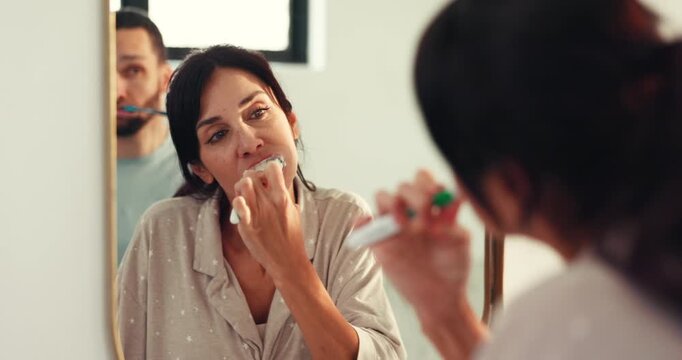 Mirror, brushing teeth and couple in bathroom, oral hygiene and wellness with morning routine. Home, reflection and man with woman, dental health and cleaning mouth with tooth care and remove plaque