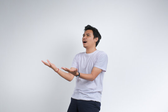 A young man in a white t-shirt expressing confusion or questioning with open hands gesture. Studio shot on plain background showing human emotion.