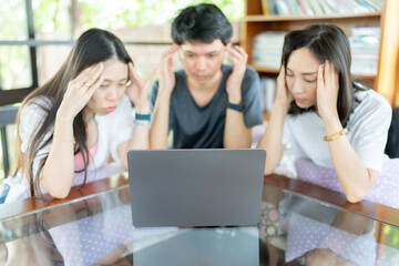 Inside the quiet university library, a Group of 3 Asian students spends hours tutoring, reading course materials, and using a laptop to complete assignments and achieve academic excellence.