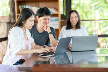 Working late in the university, 3 Asian students collaborate on a project, depending on a laptop to research education methods, industry standards, and possibilities for the future.