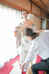 A woman in a kimono is being helped by a man to adjust her outfit. Concept of care and attention to...