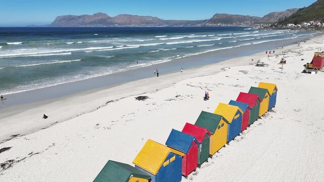 drone fly ab ove white sand beach whit colourful hut in Cape Town South Africa
