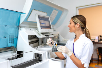 Lab tech loading samples into a chemistry analyzer. female lab tech loading specimen for coagulation test analysis