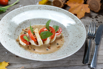 salad with toatti cheese in sauce in a plate on a wooden background macro photo