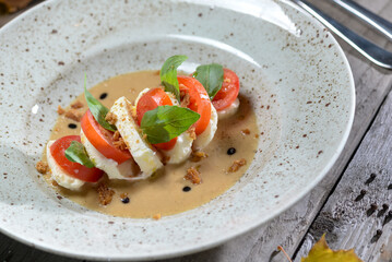 salad with toatti cheese in sauce in a plate on a wooden background